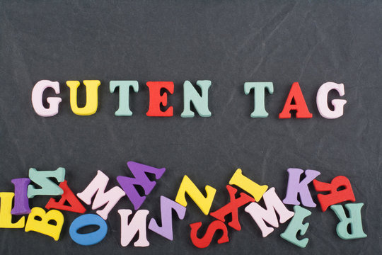 GUTEN TAG word on black board background composed from colorful abc alphabet block wooden letters, copy space for ad text. Learning english concept.