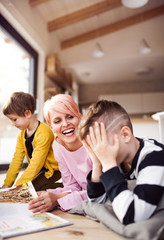 A young woman with two children reading book and playing on the floor.