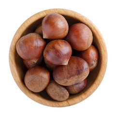 Fresh raw edible sweet chestnuts in wooden bowl isolated on white. Top view. Close-up.