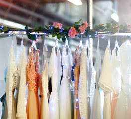 Few elegant wedding, bridesmaid ,evening, ball gown or prom dresses on a hanger in a bridal shop. © Maria Sbytova