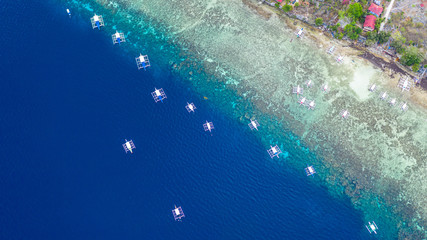 Aerial view of Filipino boats floating on top of clear blue waters, Moalboal is a deep clean blue...