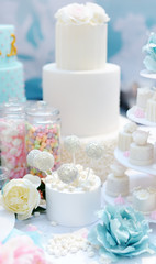 Fototapeta na wymiar Traditional anniversary/wedding multi-layer cake decorated with flowers. And beautiful delicious sweet dessert - cupcakes, marshmallow, vanilla cake pops. Stylish sweet table.