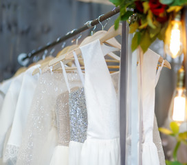 Few elegant wedding, bridesmaid ,evening, ball gown or prom dresses on a hanger in a bridal shop.