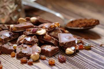 Chocolate with huzelnuts, raisins  on wooden table. Close up with selective focus.