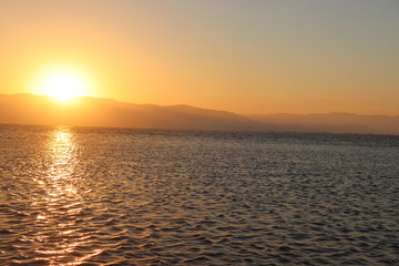 Naklejka premium Atardecer tras las montañas en un lago