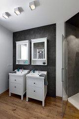 interiors shots of a modern bathroom with wooden floor in the foreground two wash basins cabinets