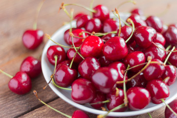 fresh ripe cherries in a plate on a wooden table