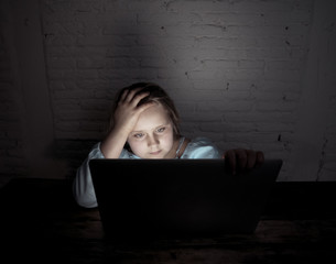 Sad young girl with laptop suffering bullying and harassment online. Cyber bullying victim
