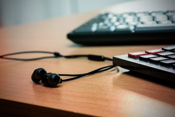 keyboard, calculator and headphones on desk, focus on headphones