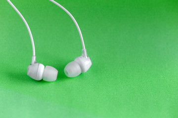 White earbuds on green colorful background with copy space for text