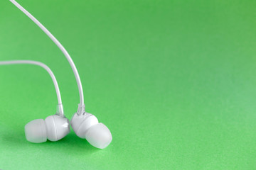 White earbuds on green colorful background with copy space for text