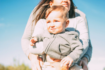 Cute baby boy with his family on sky background outdoors, sensitivity to nature concept