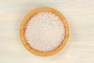 A bowl of sea salt, shot from above on a white wooden background