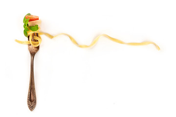 Italian pasta. A vintage fork with a very long pappardelle, basil, cheese, tomato, and pepper, on a...