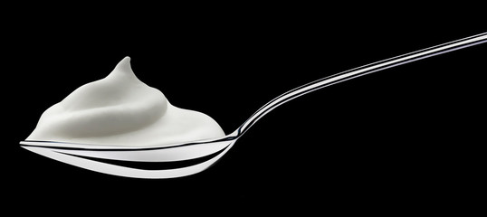 Stainless spoon of yogurt on a black background
