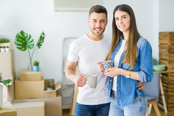 Beautiful couple moving to a new house, smiling cheerful drinking a cup of coffee