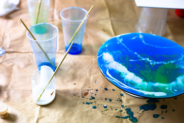 Fluid art acrylic painting. Pouring acrylic paint at circle canvas with blue and white paints on the craft paper