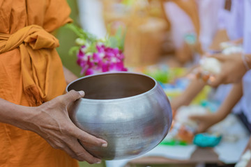 Teachers and students together make merit to give food offerings to a Buddhist monk on important...