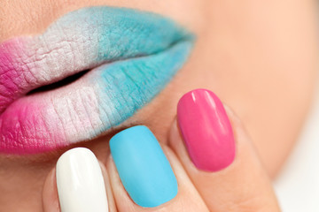 Obraz na płótnie Canvas Multi-colored lip makeup and nail design with pink, blue matte and white lacquer with different forms of nails. Manicure close-up.
