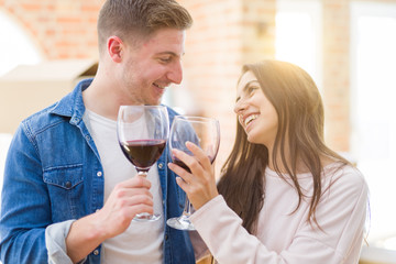 Young beautiful couple drinking a glass of wine celebrating moving to a new house