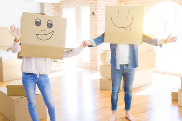 Couple having fun at new apartment wearing boxes with funny faces over head
