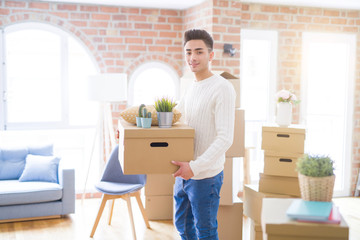 Fototapeta na wymiar Young man smiling holdig cardboard box, happy moving to a new house