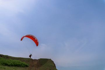 paragliding on a red paraglider flying over the sea