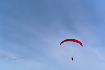 paragliding on a red paraglider flying over the sea