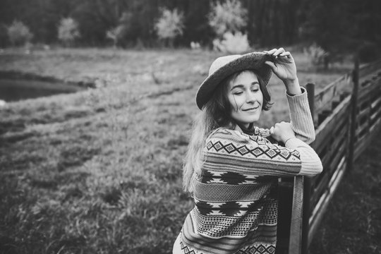 Girl in clothes with ethnic patterns posing in nature background. Portrait of smiling young woman in boho hat. close up portrait of a girl in a hat on the background of the forest in rainy day.