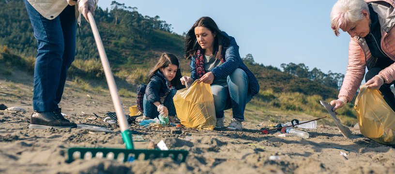 Group Of Female Volunteers Picking Up Trash On The Beach