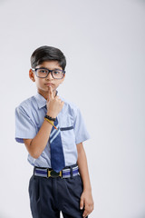 Cute little indian school boy asking / posing to keep silence, standing isolated over white background