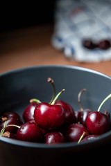 A bowl of cherries on a wooden table.
