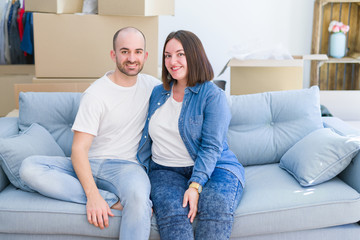 Young couple in love relaxing and hugging sitting on the sofa at new home, smiling very happy for moving to a new apartment