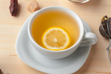 Top view of a cup of tea with lemon piece on wooden table