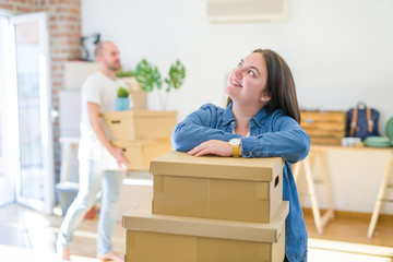 Fototapeta na wymiar Young couple moving to new apartment, beautiful woman leaning on cardboard boxes and smiling happy