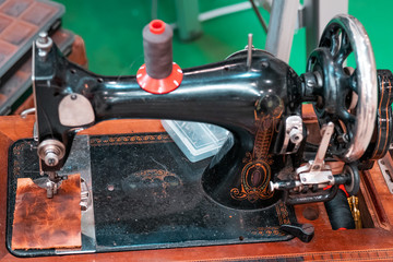 Close up shot of an old vintage sewing machine. Traditional handcraft, 19th century industrial technology. Taylor working and stitching a leather patch. 