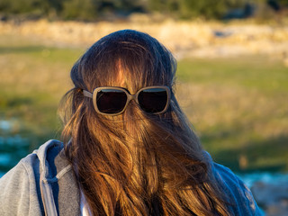 A curvy woman making funny gestures with hair in front of his face and sunglasses