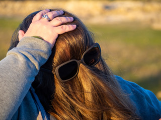 A curvy woman making funny gestures with hair in front of his face and sunglasses