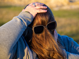 A curvy woman making funny gestures with hair in front of his face and sunglasses