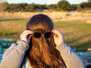 A curvy woman making funny gestures with hair in front of his face and sunglasses
