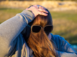 A curvy woman making funny gestures with hair in front of his face and sunglasses