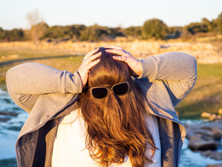 A curvy woman making funny gestures with hair in front of his face and sunglasses