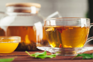 glass teapot with cup of black tea on wooden table