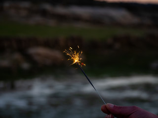 An unrecognizable person with a sparkler sizzling in his hand