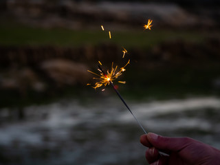 An unrecognizable person with a sparkler sizzling in his hand