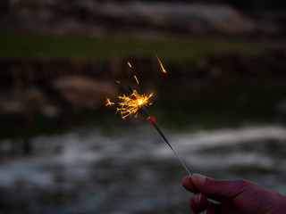 An unrecognizable person with a sparkler sizzling in his hand
