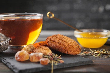 Cup of tea with lemon and honey on wooden background.