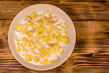 Ceramic plate with cornflakes and milk on a wooden table. Healthy eating. Top view