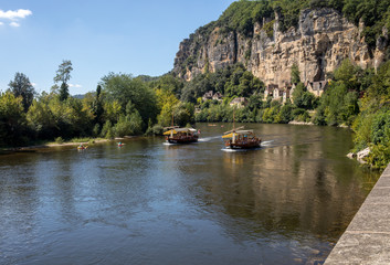 Fototapeta na wymiar Canoeing and tourist boat, in French called gabare, on the river Dordogne at La Roque-Gageac, Aquitaine, France