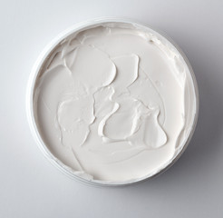 thick white cosmetic cream in a plastic jar, top view